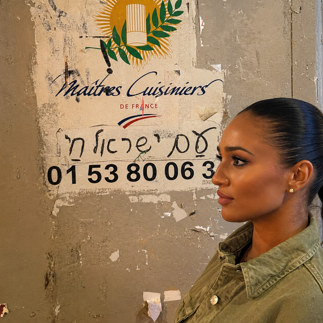 A Jewish woman wearing a Magen David beside Hebrew writing on a wall in France